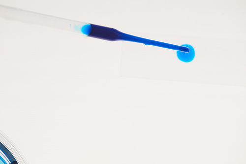 Close-up of tube with blue liquid over white background