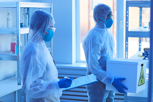 People in protective costumes working in the laboratory together with chemicals