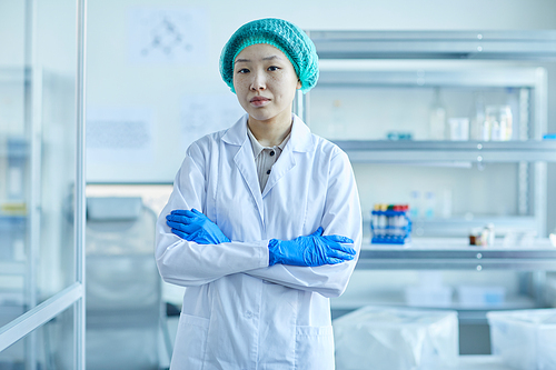 Portrait of Asian female doctor in white coat standing with her arms crossed and looking at camera at office