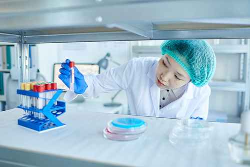 Asian woman in protective gloves working as a nurse she working with samples and test tubes in the lab
