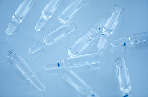 Close-up of glass capsules with medicine inside of it isolated on blue background