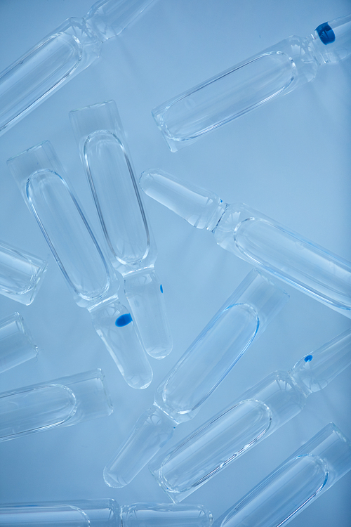 Close-up of glass capsules with medicine to treat the sick people over blue background
