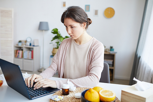 Young woman sitting at the table and typing on laptop computer she working online at work