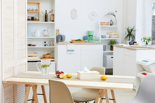 Image of wooden kitchen table with lemonade and fruits on it in domestic kitchen