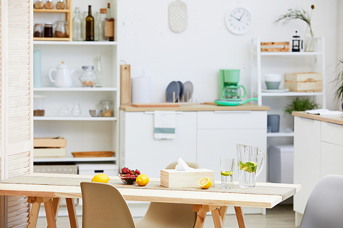 Image of domestic kitchen with white furniture and table with drinks and fruits on it in the house