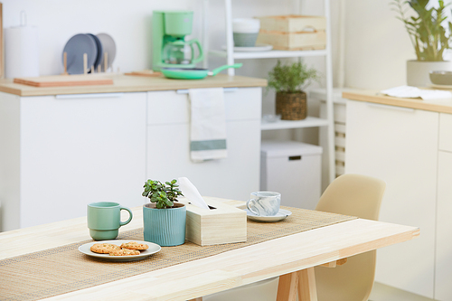 Image of biscuits and cups of coffee or tea on the wooden table in the kitchen