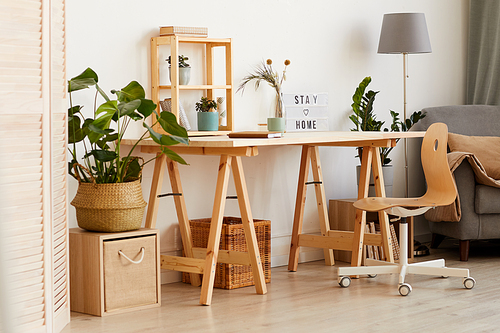 Image of modern wooden table with flowers and sofa near by in the living room at home