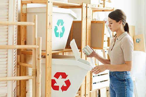 Young woman sorting waste into the plastic containers in the warehouse