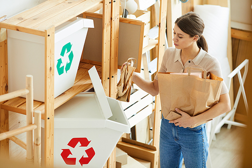 Young woman sorting paper bags into the plastic containers while standing in the warehouse