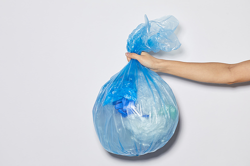 Close-up of female hand holding package with garbage against the white background