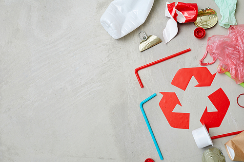 Close-up of red recycling symbol with waste isolated on grey background