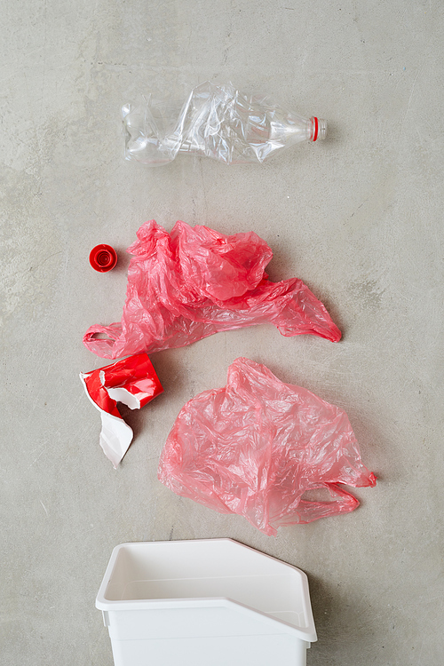 Close-up of bags and plastic bottles sorting in plastic container isolated on grey background