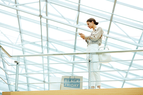 Young businesswoman using her mobile phone while standing at modern office building