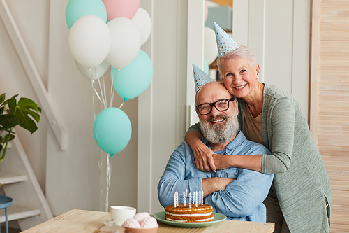 Portrait of happy senior couple embracing and smiling at camera while celebrating birthday