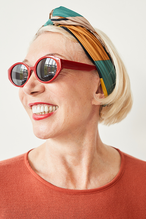 Portrait of fashion mature woman in stylish sunglasses smiling against the white background