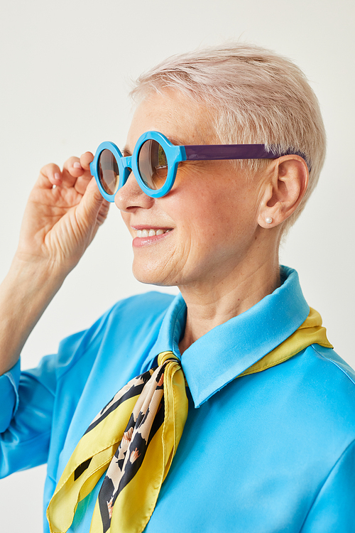 Elegant senior woman with blond short hair wearing sunglasses and smiling isolated on white background