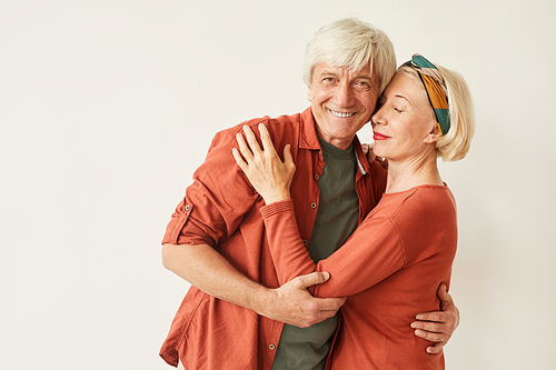 Mature loving couple embracing each other against the white background