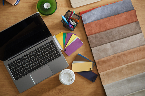High angle view of workplace of designer with laptop and fabric samples