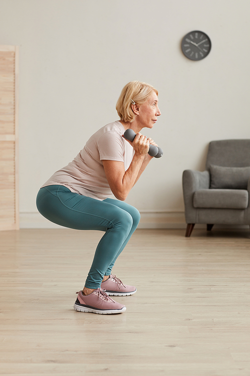 Senior woman exercising with dumbbells during sports training at home