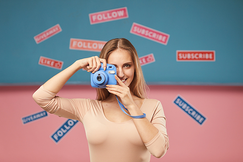 Portrait of young woman making a picture on photo camera with different placards on the background