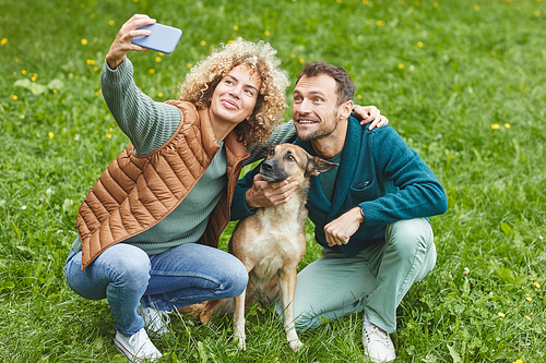 Young couple making selfie portrait on the mobile phone with their pet outdoors