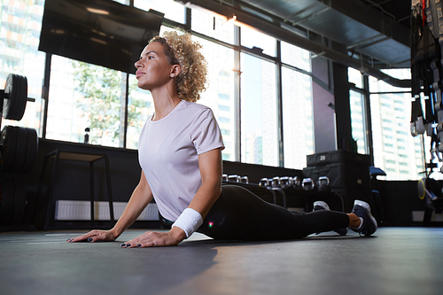 Young healthy woman doing stretching exercises on the floor in the gym