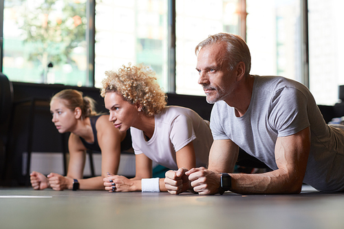 Group of healthy people doing push-ups on the floor together in healthy club