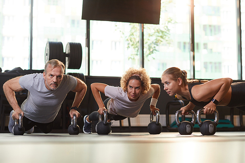 Group of healthy people training with dumbbells on the floor they doing physical exercises during training in gym