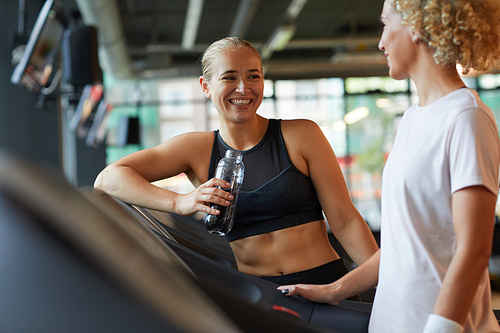 Two women smiling and talking to each other while training in gym