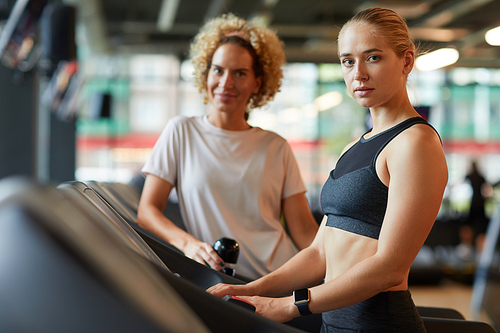 Portrait of two sportive women looking at camera while training in the gym