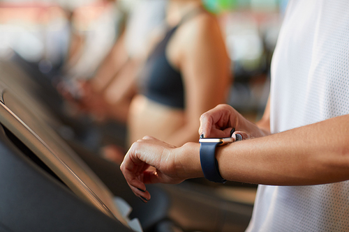 Close-up of woman checking pulse on her watch while training on treadmill in health club