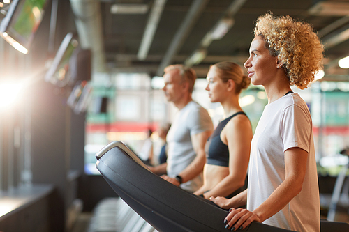 Group of healthy people exercising on treadmills during sports training in health club