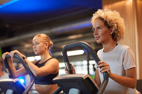 Two young women training on treadmills in modern gym