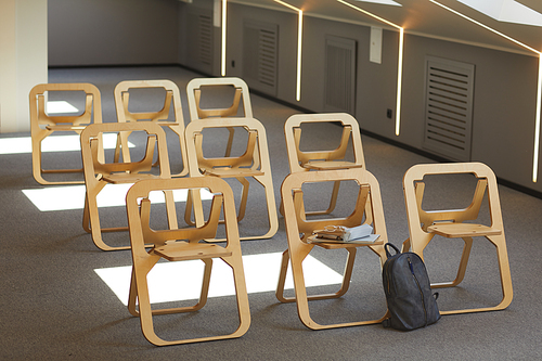 Empty lecture room with modern wooden folding chairs in rows and satchel near one of it