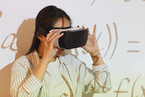 Young Asian woman using virtual reality app for equation solution at university class