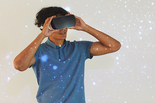 Content mixed race guy in blue tshirt adjusting virtual reality goggles while watching virtual effects