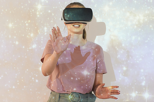 Smiling young woman standing against projection screen with glittering star sky while studying astronomy with virtual reality simulator