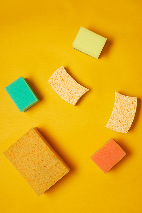 Image of different colorful sponges for housework isolated on yellow background