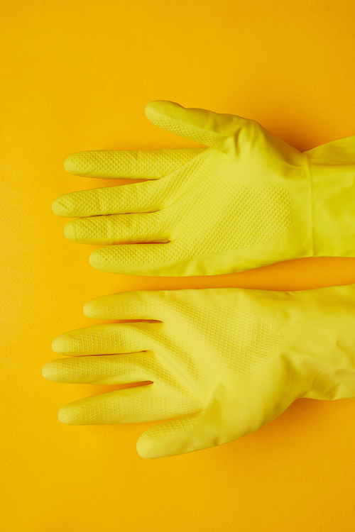 Close-up of yellow rubber gloves isolated on yellow background