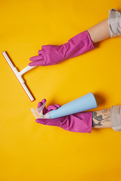 Close-up of woman in rubber gloves cleaning the surface with sponge and cleanser spray