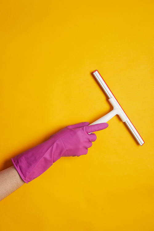 Close-up of woman in rubber gloves using sponge to clean the surface isolated on yellow background