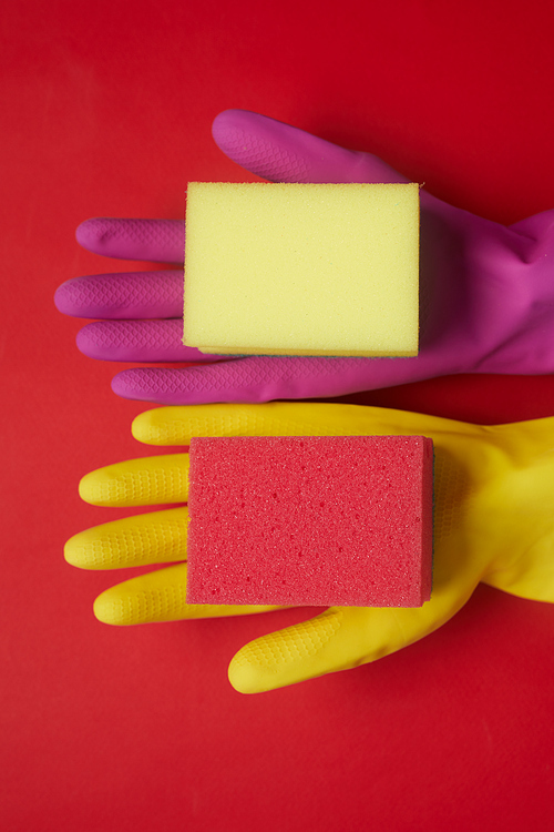 High angle view of colorful rubber gloves and sponges for cleaning isolated on red background