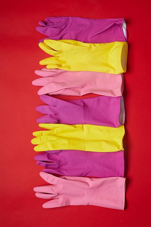 High angle view of colorful rubber gloves lying in a row isolated on red background