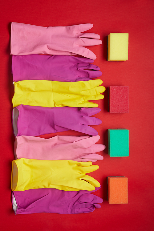 High angle view of rubber gloves and sponges lying in a row isolated on red background