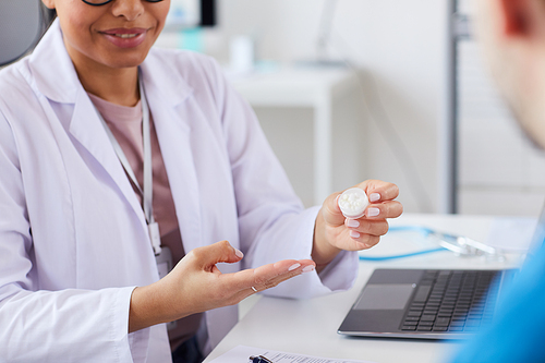Close-up of female doctor holding pills in her hand and prescribing them to the patient