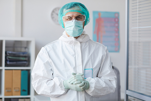 Portrait of male doctor in protective workwear and mask looking at camera while working at hospital