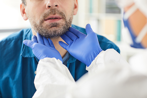 Close-up of doctor in protective gloves examining the patient's throat during his visit