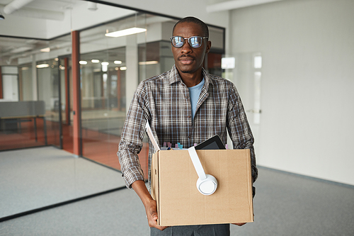 Portrait of African businessman holding box with his stuffs while standing at office he fired from work