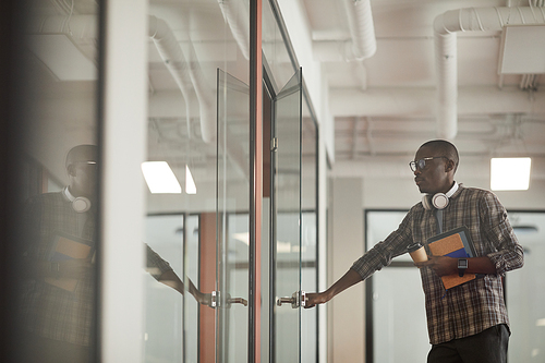 African young man in casual clothing opening the door of board room he coming at meeting