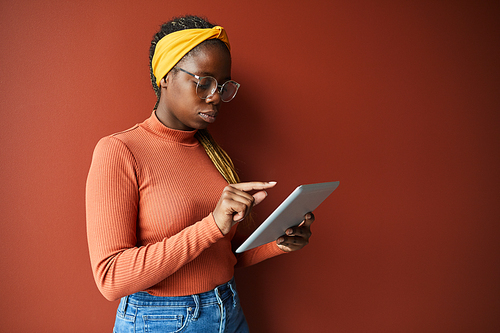 African young woman in eyeglasses concentrating on her online work she using digital tablet